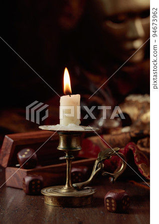 Burning candle, dice, and carnival masks. 94673962