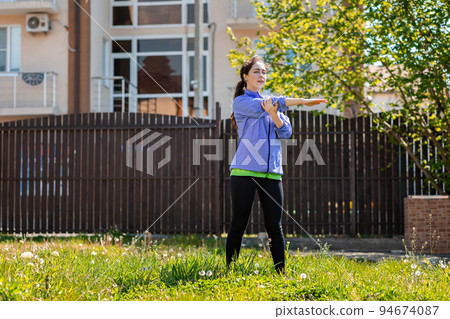 A young woman in sports clothes is doing yoga in her yard, on the grass. Outdoor. The concept of a healthy lifestyle and home sports 94674087