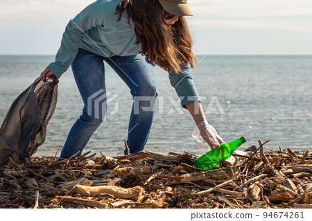 Girl volunteer helps clean the beach of debris. Earth day and environmental improvement concept 94674261