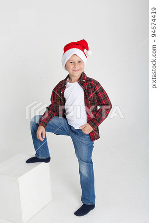 Little boy in santa hat with gingerbread house on white background. Happy new year's card. Waiting for the holiday. 94674419