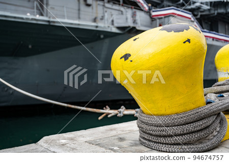 Selective focus on line securing a naval boat to a port bollard. Selective focus on line securing a naval boat to a port bollard. 94674757