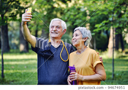 Old sportive couple using smartphone outdoors 94674951