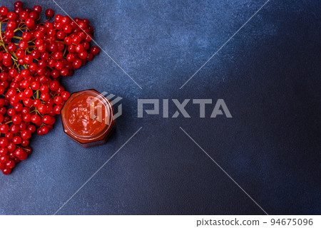 Viburnum fruit jam in a glass jar on a dark concrete background 94675096