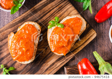 Ajvar delicious appetizer of pepper, eggplant and garlic on bread and in bowls. Top view. Closeup 94675418