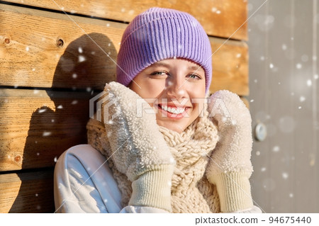 Winter portrait of young woman looking at camera with snowflakes on face Winter portrait of young woman looking at camera with snowflakes on face 94675440