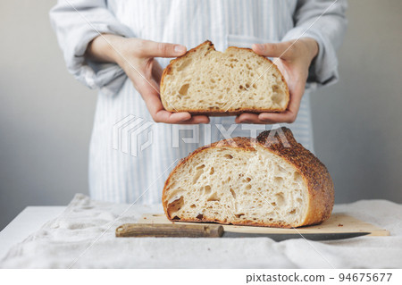 woman baker cooks bread in the kitchen, a cook in a pastry shop holds bread in her hands 94675677