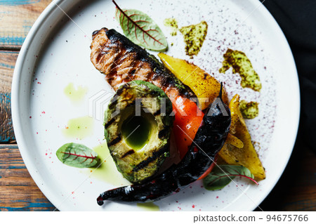 Grilled salmon fish fillet with vegetables and avocado on the plate, close up 94675766