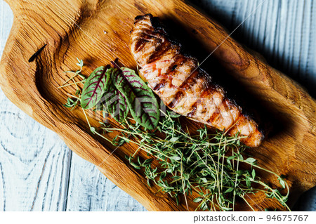 Grilled salmon fish fillet with green salad on the wooden cutting board, close up 94675767