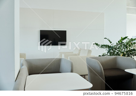 Part of modern openspace office with tv screen on wall, armchairs and tables Part of modern openspace office with tv screen on wall, armchairs and tables 94675816