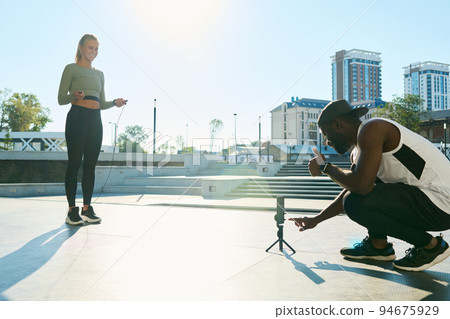Young African American sportsman pointing at smartphone screen before shooting Young African American sportsman pointing at smartphone screen before shooting 94675929