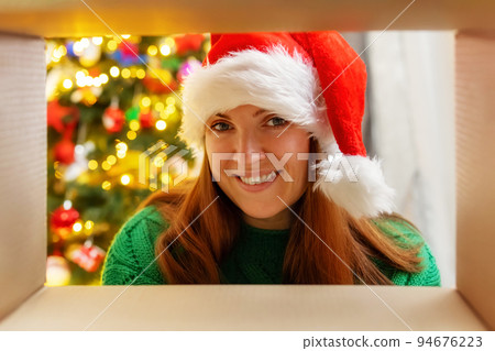 Young woman opening Christmas present, view from inside the box Young woman opening Christmas present, view from inside the box 94676223