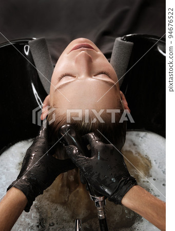 Young woman in a hairdressing salon dyes her hair blond and washing head Young woman in a hairdressing salon dyes her hair blond and washing head 94676522
