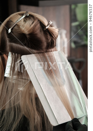 Young woman in a hairdressing salon dyes her hair blond 94676537
