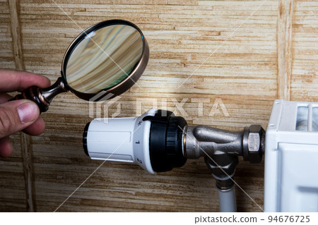 Magnifying glass in man's hand. Heating bill and savings concept 94676725