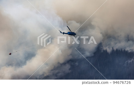 Wildfire Service Helicopter flying over BC Forest Fire and Smoke on the mountain near Hope 94676726