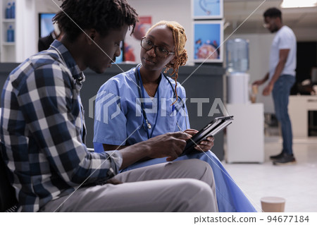 African american specialist and man talking about disease, doing checkup consultation with sick man in hospital waiting area. Medical assistant examining person to give medication, health center. African american specialist and man talking about disease, doing checkup consultation with sick man in hospital waiting area. Medical assistant examining person to give medication, health center. 94677184