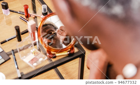Black transgender man applying makeup 94677332