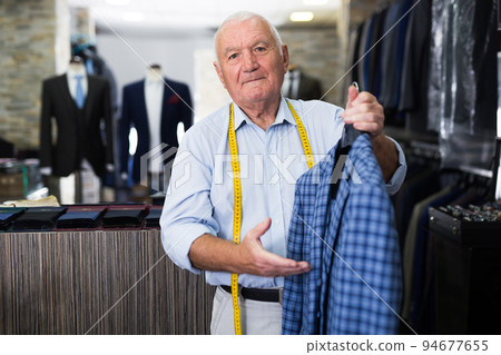 Male tailor demonstrating of fashionable suit in apparel shop Male tailor demonstrating of fashionable suit in apparel shop 94677655