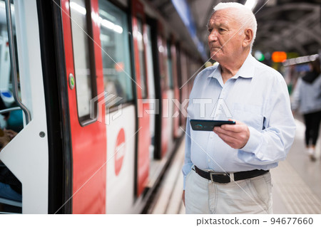 Senior man standing in front of subway train 94677660