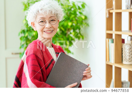 Portrait of a gray-haired woman reading 94677858