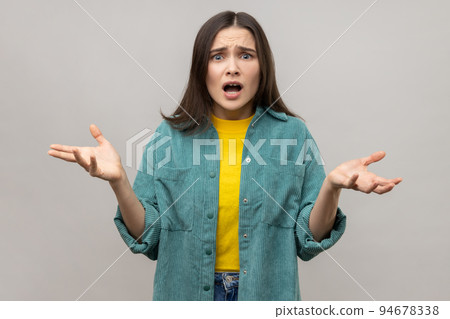 How could you. Disgruntled woman with dark hair indignantly asking reason of failure, claims in conflict, why hand gesture, wearing casual style jacket. Indoor studio shot isolated on gray background. 94678338