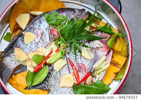 cooking tilapia with herb spice cannabis leaf ginger garlic pepper chili on steamer, Fresh raw tilapia for cooking food cooking tilapia with herb spice cannabis leaf ginger garlic pepper chili on steamer, Fresh raw tilapia for cooking food 94679357