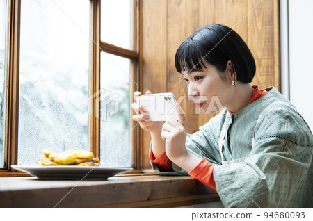 Young woman taking photo of homemade pancakes 94680093