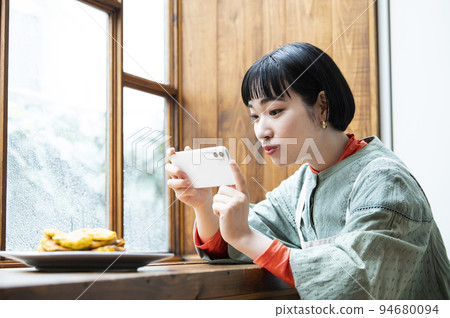 Young woman taking photo of homemade pancakes Young woman taking photo of homemade pancakes 94680094