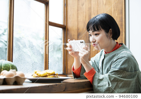 Young woman taking photo of homemade pancakes Young woman taking photo of homemade pancakes 94680100