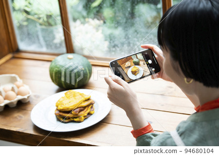 Young woman taking photo of homemade pancakes 94680104