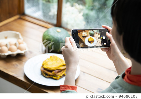 Young woman taking photo of homemade pancakes Young woman taking photo of homemade pancakes 94680105