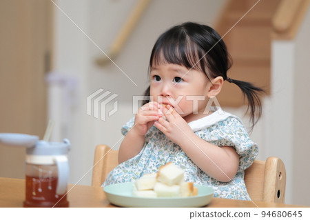 A 1-year-old girl who grabs and eats bread A 1-year-old girl who grabs and eats bread 94680645