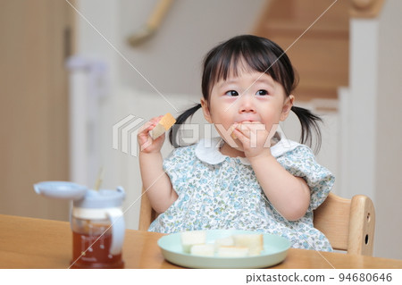 A 1-year-old girl who grabs and eats bread A 1-year-old girl who grabs and eats bread 94680646