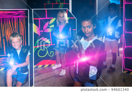 Teenager girl with laser pistol in her hands playing laser tag game Teenager girl with laser pistol in her hands playing laser tag game 94681340