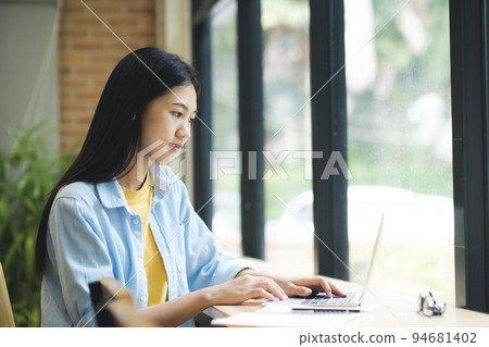 Young asian woman studying using laptop and sitting at table. Young asian woman studying using laptop and sitting at table. 94681402