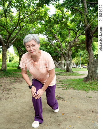 A 60-year-old Asian mature woman stretches her thighs and thighs, enjoys the fresh air of nature in the park. 94681632