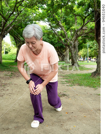 A 60-year-old Asian mature woman stretches her thighs and thighs, enjoys the fresh air of nature in the park. 94681640