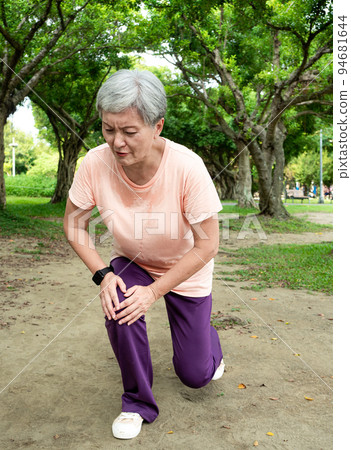 A 60-year-old Asian mature woman stretches her thighs and thighs, enjoys the fresh air of nature in the park. 94681644