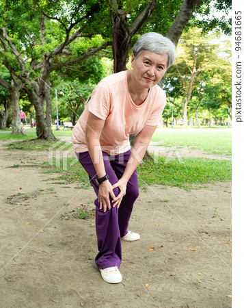 Mature Asian woman in her 60s exercising outdoors feeling uncomfortable with sore knee. 94681665