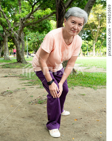 Mature Asian woman in her 60s exercising outdoors feeling uncomfortable with sore knee. 94681669