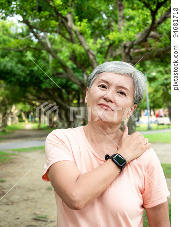 Mature Asian woman in her 60s is uncomfortable with sore shoulders exercising outdoors Mature Asian woman in her 60s is uncomfortable with sore shoulders exercising outdoors 94681718