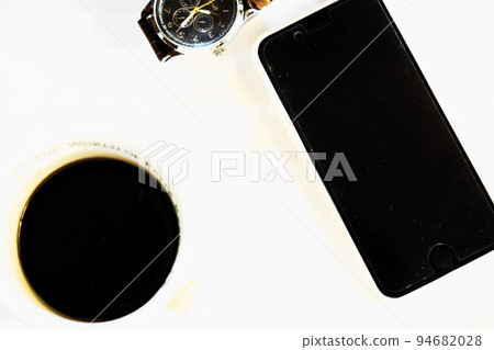 A coffee cup, a smartphone and a watch on a white table A coffee cup, a smartphone and a watch on a white table 94682028
