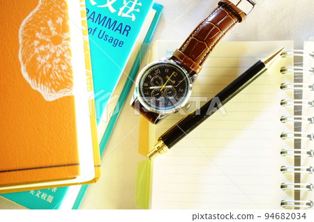 Notebooks, pens, wristwatches, piled up dictionaries placed in double-page spreads 94682034