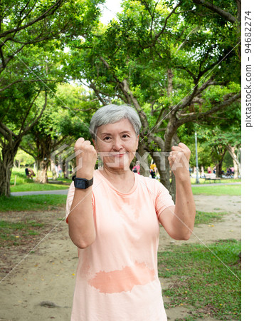 Portrait of happy senior adult elderly asia woman 60s doing winner gesture celebrating clenching fist say yes isolated in the park. 94682274