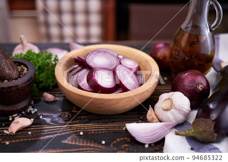 Sliced in circles Red Onion in wooden bowl on dark background Sliced in circles Red Onion in wooden bowl on dark background 94685322