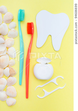 Tooth model, toothbrush and seashells. Yellow background. Flat lay. Top view. Benefits of minerals for dental hygiene. Oral care. Strength of teeth and gums. Vertical. Gum health. Tooth model, toothbrush and seashells. Yellow background. Flat lay. Top view. Benefits of minerals for dental hygiene. Oral care. Strength of teeth and gums. Vertical. Gum health. 94686699