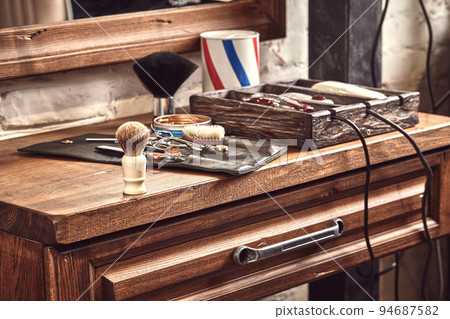 Hairdresser tools on wooden background. Top view on wooden table with scissors, comb, hairbrushes and hairclips, trimmer. 94687582
