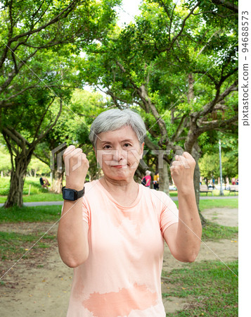 A 60-year-old happy silver-haired Asian elderly woman in the park celebrates the celebration with a tight fist. 94688573