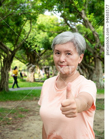 一位 60 歲的快樂老婦人在公園裡豎起大拇指。 94688577
