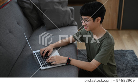 Happy man sitting in living room and learning online on laptop. Education, e-learning, distance training Happy man sitting in living room and learning online on laptop. Education, e-learning, distance training 94688909